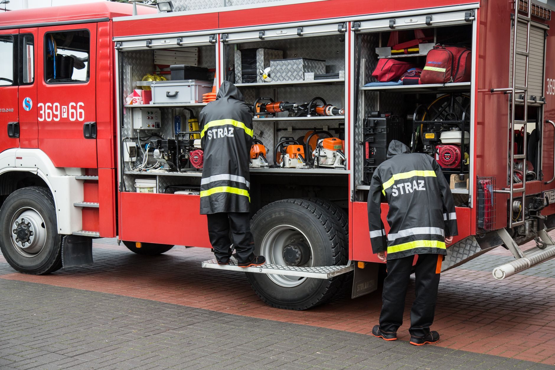 Firefighters in turnout gear working at the side of a fire engine