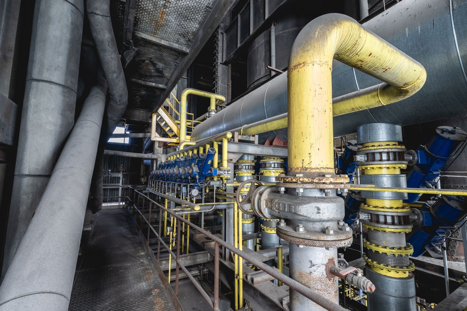 The inside of a pipeline valve station with yellow piping and valve actuators